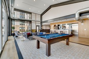 a common room with a pool table and lounge area